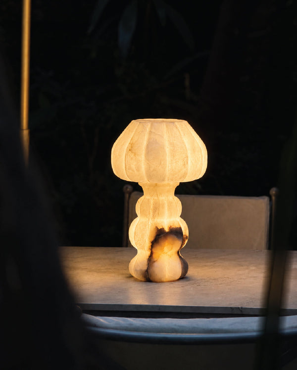 Noura Table Lamp softly illuminating a dim interior space